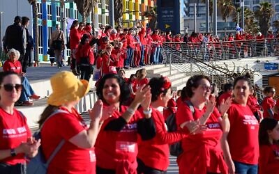 Hundreds of women dressed in red mark International Women's Day and demonstrate against the government's planned judicial overhaul, on the beach in Tel Aviv, March 8, 2023. (Tomer Neuberg/Flash90)