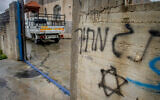 The scene where Palestinian-owned cars and the wall of a home was graffitied in a suspected settler hate crime in the West Bank city of Salfit, March 20, 2023. (Nasser Ishtayeh/Flash90)