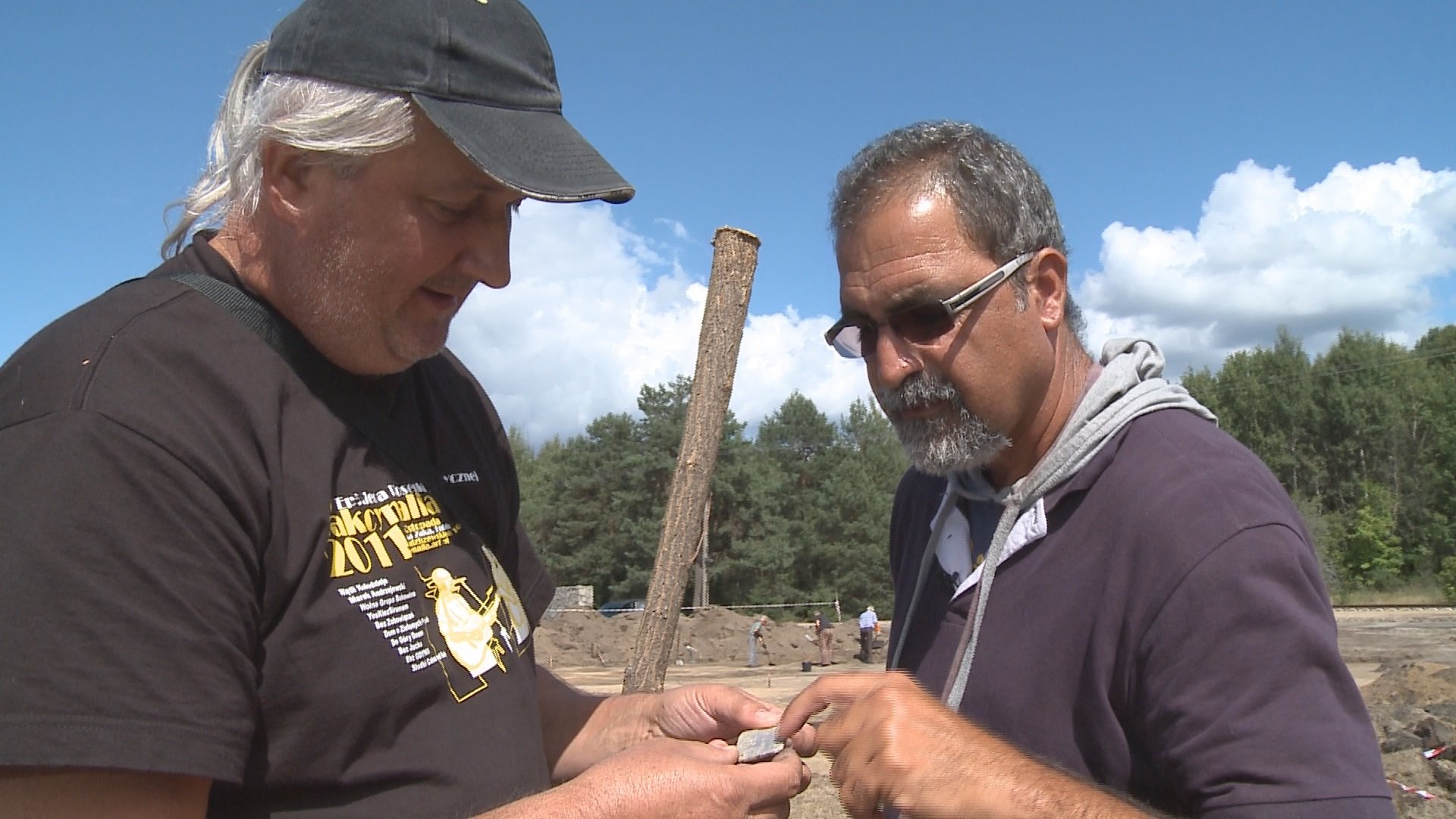 Wojceich Mazurek (left) and Yoram Haimi examine the nametag of Judith de la Penha at Sobibor (courtesy: Gary Hochman)