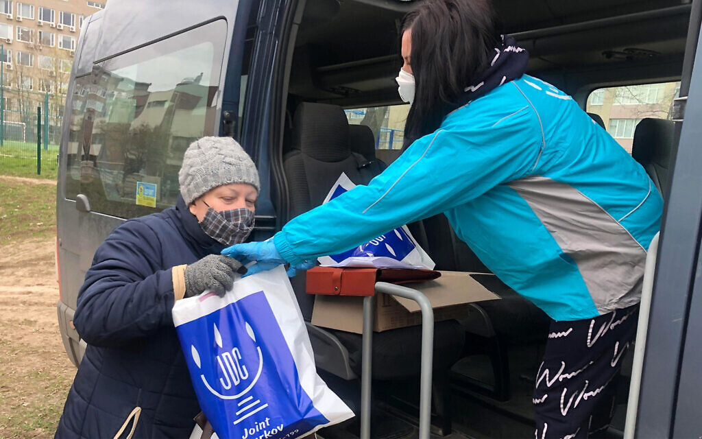 An employee of the American Jewish Joint Distribution Committee, right, hands out an aid package to a Jewish woman in Kharkiv, Ukraine during the coronavirus pandemic in March 2020. (Courtesy of JDC) An employee of the American Jewish Joint Distribution Committee, right, hands out an aid package to a Jewish woman in Kharkiv, Ukraine during the coronavirus pandemic in March 2020. (Courtesy of JDC)