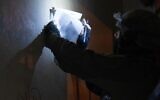 An Israeli soldier takes measurements at the home of a Palestinian gunman who killed an Israeli soldier, in the West Bank city of Nablus, early February 20, 2023. (Israel Defense Forces)
