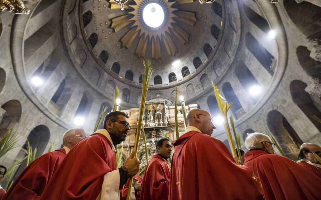 Roman Catholic clergymen walk with palm fronds as they circle in a procession around the Edicule, traditionally believed to be the burial site of Jesus Christ, at the Church of the Holy Sepulchre in Jerusalem on April 2, 2023, Palm Sunday according to Catholic Christians. (Photo by MENAHEM KAHANA / AFP)