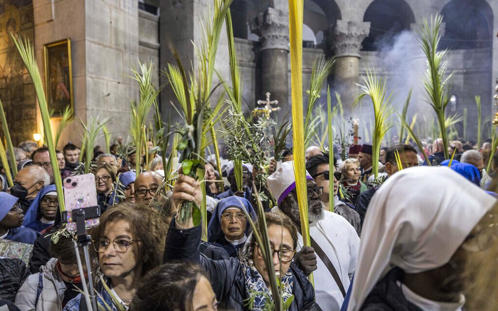 Christian pilgrims walk with palm fronds as they circle in a procession around the Edicule, traditionally believed to be the burial site of Jesus Christ, at the Church of the Holy Sepulchre in Jerusalem on April 2, 2023, Palm Sunday according to Catholics. (Photo by MENAHEM KAHANA / AFP)