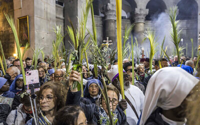 Christian pilgrims walk with palm fronds as they circle in a procession around the Edicule, traditionally believed to be the burial site of Jesus Christ, at the Church of the Holy Sepulchre in Jerusalem on April 2, 2023, Palm Sunday according to Catholics. (Photo by MENAHEM KAHANA / AFP)