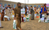 Illustrative: Men carry humanitarian aid provided by a Kuwaiti charitable organization during a distribution to displaced Yemenis on the outskirts of the northeastern city of Marib on April 6, 2023. (Photo by STR / AFP)