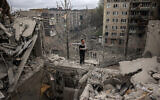 A volunteer gesticulates on top of a partially destroyed residenial building after a shelling in Sloviansk, Donetsk region on April 14, 2023, amid the Russian invasion of Ukraine. (Photo by ANATOLII STEPANOV / AFP)
