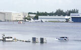 A truck drives on the flooded runway at Fort Lauderdale- Hollywood International Airpor, April 13, 2023, in Fort Lauderdale, Florida. (AP Photo/Marta Lavandier)