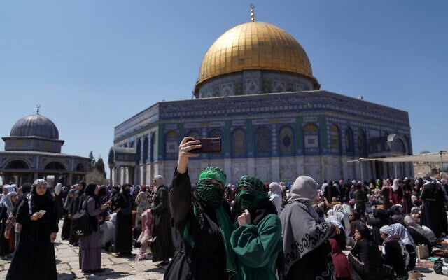 A pair of Muslim women worshippers, one wearing a headband in support of Hamas' military wing, the Qassam Brigades, take a photo as they gather for Friday prayers next to the Dome of Rock at the Al-Aqsa Mosque compound in the Old City of Jerusalem during the Muslim holy month of Ramadan, Friday, April 14, 2023. (AP Photo/Mahmoud Illean)