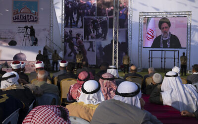 Palestinians watch a pre-recorded speech by Iranian President Ebrahim Raisi on "Jerusalem Day," which is called al-Quds Day after the city's Arabic name, at a soccer filed in Gaza City, Friday, April 14, 2023. (AP Photo/Fatima Shbair)