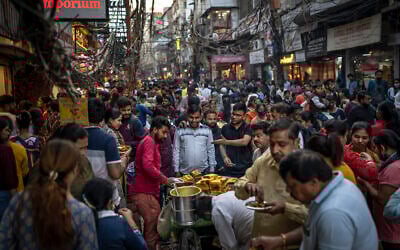 People eat street food as shoppers crowd a market in New Delhi, India, Nov. 12, 2022 (AP Photo/Altaf Qadri, File)