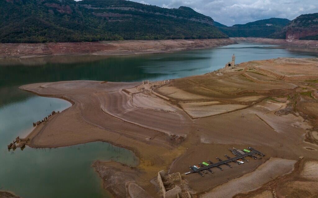 Dry, cracked land is visible around at the Sau reservoir, about 100 km (62 miles) north of Barcelona, Spain, Tuesday, April 18, 2023. (AP/Emilio Morenatti)