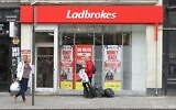 People walk past a Ladbrokes betting shop in London, Wednesday June 22, 2016. (AP Photo/Leonora Beck)