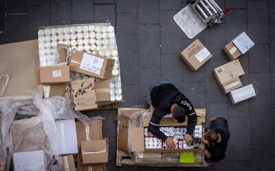 Workers unload goods outside a supermarket, in downtown Jerusalem, December 8, 2022. (Nati Shohat/Flash90)