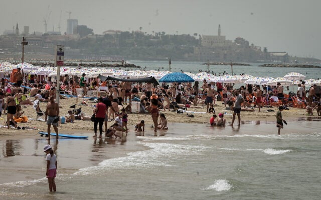 People enjoy the beach in Tel Aviv, during the Passover holiday, April 9, 2023. (Avshalom Sassoni/Flash90)
