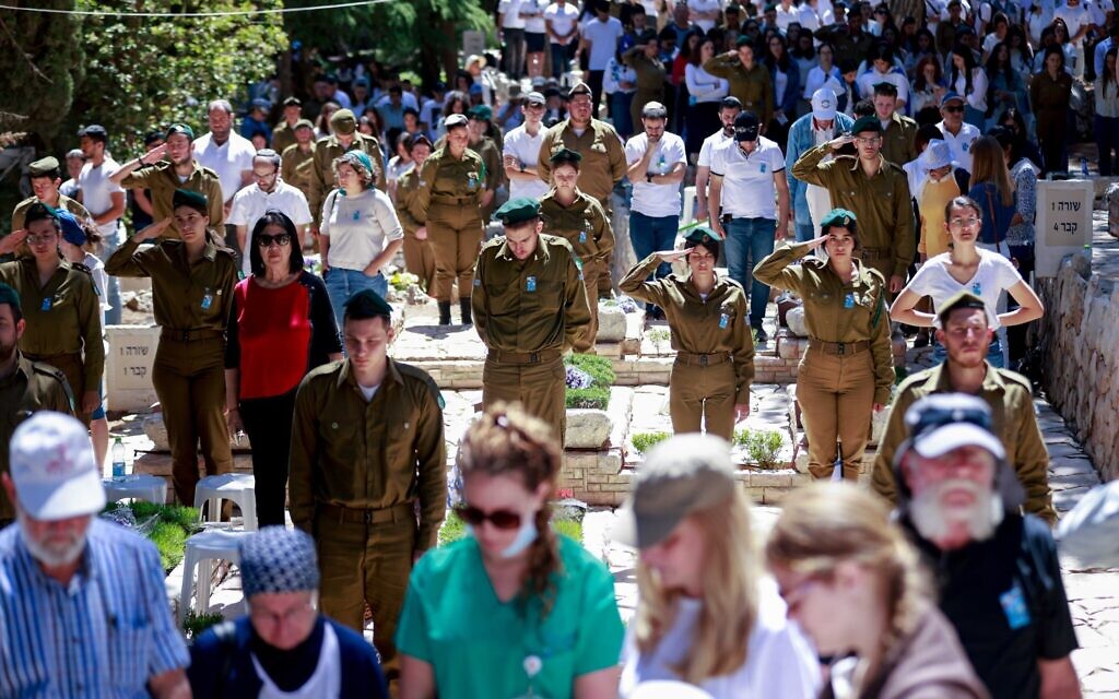 Israelis stand in silence next to graves of soldiers at the Mount Herzl miitary cemetery in Jerusalem during the Memorial Day siren, April 25, 2023. (Erik Marmor/Flash90)