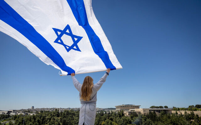 A woman waves a flag while facing the Knesset in Jerusalem, April 26, 2023. (Yonatan Sindel/Flash90 )