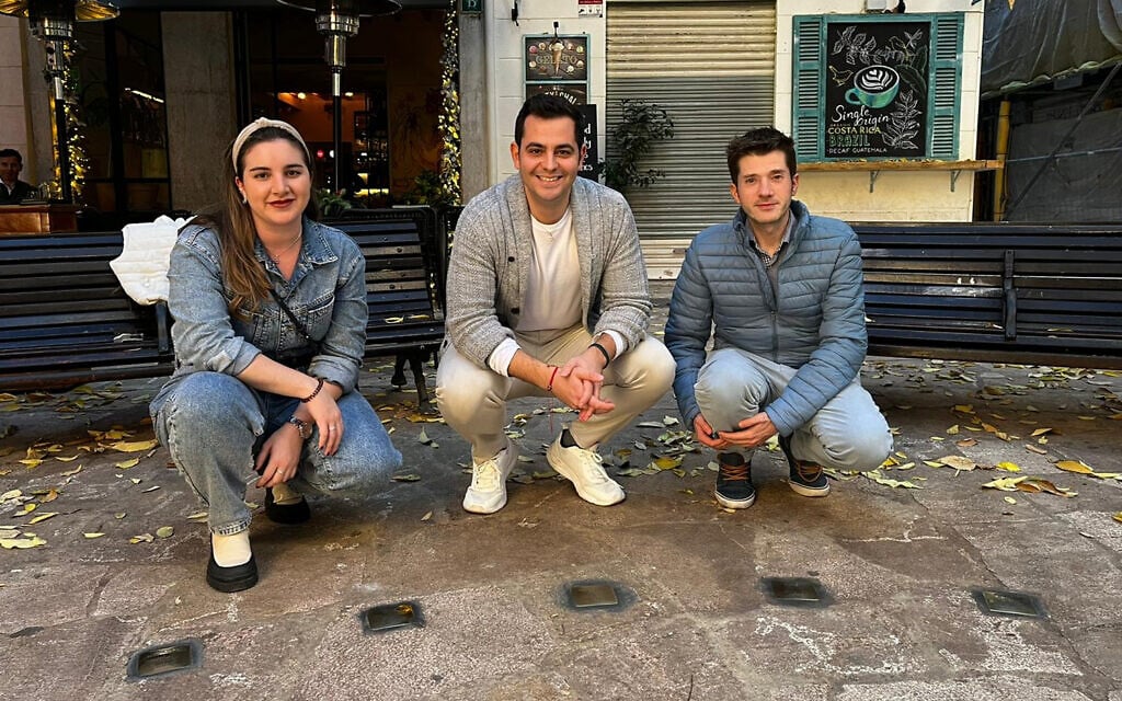 Volunteers from JewishMallorca clean Stolpersteine (stumbling stones) in Palma de Mallorca, Spain, December 12, 2022. (Courtesy of MakeTheirMemoryShine)