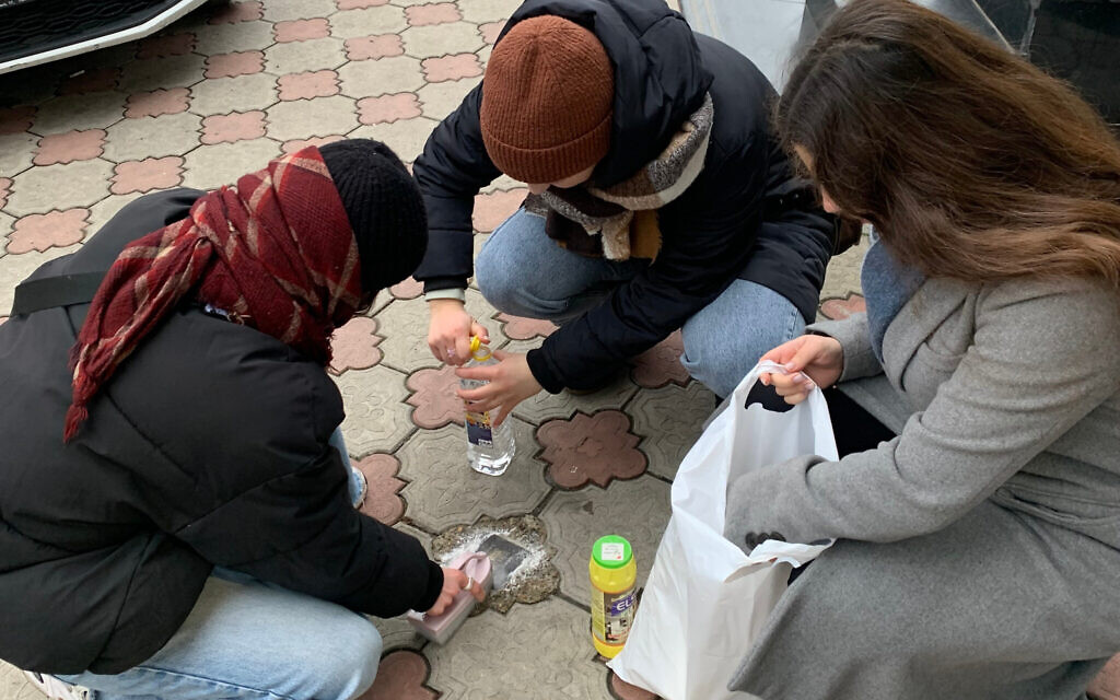 Jewish volunteers clean Slpersteine (stumbling stones) in Chisinau, Moldova, November 30, 2022 (Courtesy of Moishe House Chisinau)
