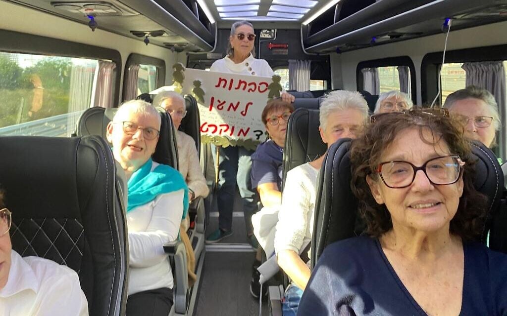 Women taking part of the "Savtot for Democracy" protest take a bus from an assisted living facility to the Tel Aviv demonstration, April 20, 2022. The placard reads, Grandmothers for democracy. (Rossie Gelb)