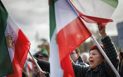 File: Protestors wave Iranian pre-Islamic Revolution flags in front of the United Nations headquarters as they attend a rally amid a special session of the UN Human Rights Council on the situation in Iran, in Geneva on November 24, 2022. (VALENTIN FLAURAUD/AFP)
