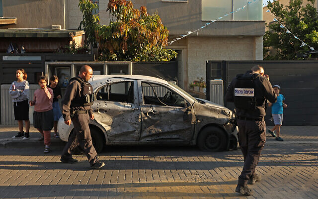 Security forces inspect a damaged car in the southern city of Sderot following rocket fire from Gaza on May 2, 2023. (Gil Cohen-Magen/AFP)