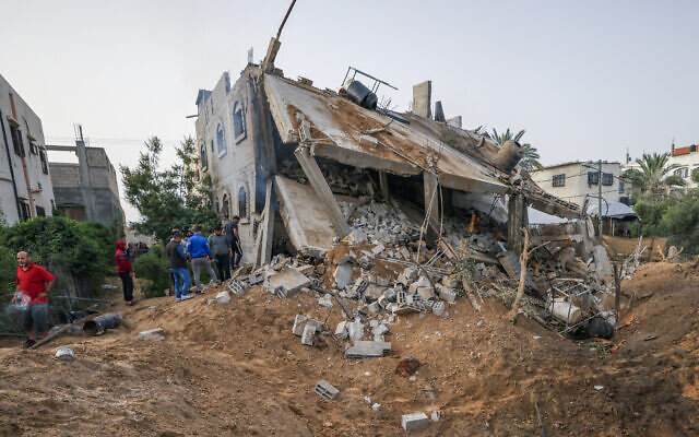 Illustrative: People gather near a destroyed building following an Israeli airstrike in Deir el-Balah, central Gaza Strip, on May 12, 2023, amid fighting between Israel and the Palestinian Islamic Jihad terror group. (Mahmud Hams/AFP) Illustrative: People gather near a destroyed building following an Israeli airstrike in Deir el-Balah, central Gaza Strip, on May 12, 2023, amid fighting between Israel and the Palestinian Islamic Jihad terror group. (Mahmud Hams/AFP)