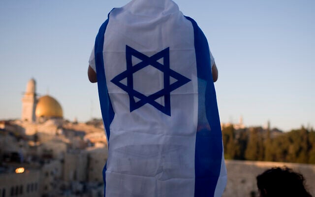 FILE: With the Dome of the Rock on the right, an Israeli man covered in a flag watches Israelis wave the national flag as they march in the Jerusalem Day parade in Jerusalem's Old City, June 1, 2011. (AP Photo/Ariel Schalit)