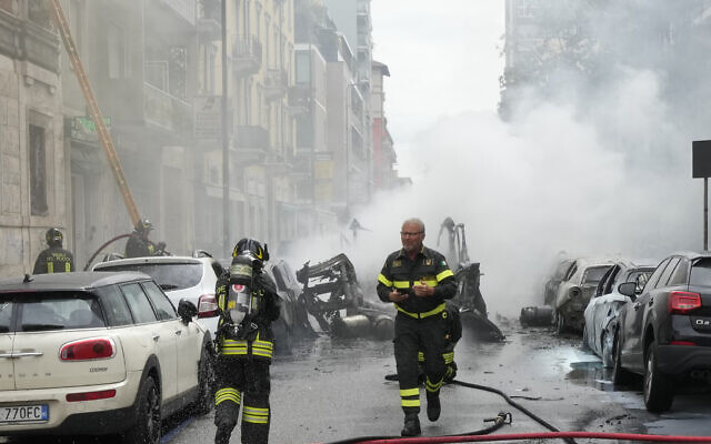 Firefighters work to extinguish a fire in a building after a van exploded in central Milan, northern Italy, Thursday, May 11, 2023. (AP Photo/Luca Bruno)