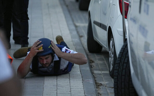 An Israeli paramedic takes cover as a siren sounds warning of incoming rockets fired from the Gaza Strip, in the southern Israeli town of Sderot, May 11, 2023. (AP Photo/Ohad Zwigenberg) An Israeli paramedic takes cover as a siren sounds warning of incoming rockets fired from the Gaza Strip, in the southern Israeli town of Sderot, May 11, 2023. (AP Photo/Ohad Zwigenberg)