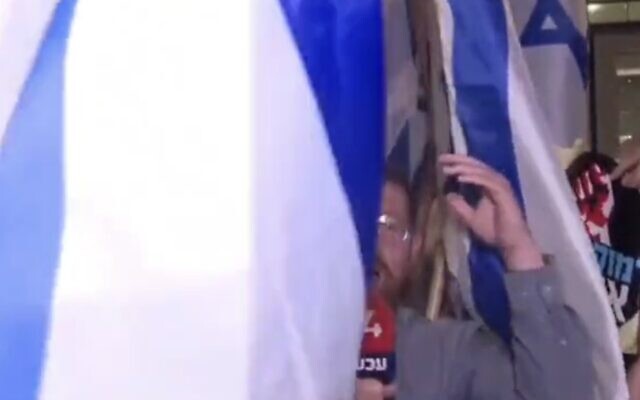 Screen capture from video of Channel 14 reporter Atay Shalev swamped by anti-government protesters at a rally in Bnei Brak, May 18, 2023. (Twitter. Used in accordance with Clause 27a of the Copyright Law) Screen capture from video of Channel 14 reporter Atay Shalev swamped by anti-government protesters at a rally in Bnei Brak, May 18, 2023. (Twitter. Used in accordance with Clause 27a of the Copyright Law)