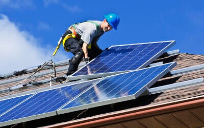 Installing solar panels on a roof. (Elenathewise, iStock at Getty Images)