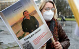 A woman holds a photo of Benjamin Briere, a captive of Iran, during a rally in Paris, France, January 8, 2022. (AP Photo/Adrienne Surprenant, File)