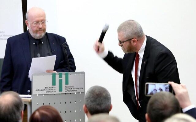 Polish-Canadian historian Jan Grabowski stands at the podium for a planned lecture as far-right lawmaker Grzegorz Braun of Poland’s Confederation party grabs the microphone and smashes it, at the German Historical Institute in Warsaw, Poland, May 30, 2023. (Courtesy of Jan Grabowski via JTA) Polish-Canadian historian Jan Grabowski stands at the podium for a planned lecture as far-right lawmaker Grzegorz Braun of Poland’s Confederation party grabs the microphone and smashes it, at the German Historical Institute in Warsaw, Poland, May 30, 2023. (Courtesy of Jan Grabowski via JTA)