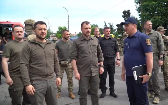 Ukrainian President Volodymyr Zelensky (front left) tours a flooding area after the collapse of the Kakhovka dam and hydroelectric plant, in Kherson, Ukraine, July 8, 2023. (Twitter video screenshot: Used in accordance with Clause 27a of the Copyright Law) Ukrainian President Volodymyr Zelensky (front left) tours a flooding area after the collapse of the Kakhovka dam and hydroelectric plant, in Kherson, Ukraine, July 8, 2023. (Twitter video screenshot: Used in accordance with Clause 27a of the Copyright Law)