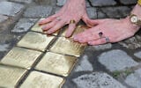 Then-US ambassador to Germany Amy Gutmann touches the freshly laid 'Stolpersteine' (stumbling stones) for members of her family in Feuchtwangen, Bavaria, on May 30, 2023. (Thomas Kienzle/AFP)