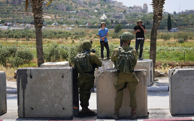 Israeli soldiers stop Israeli settlers from entering the Palestinian West Bank town of Turmus Ayya, June 21, 2023. (AP Photo/Ohad Zwigenberg)
