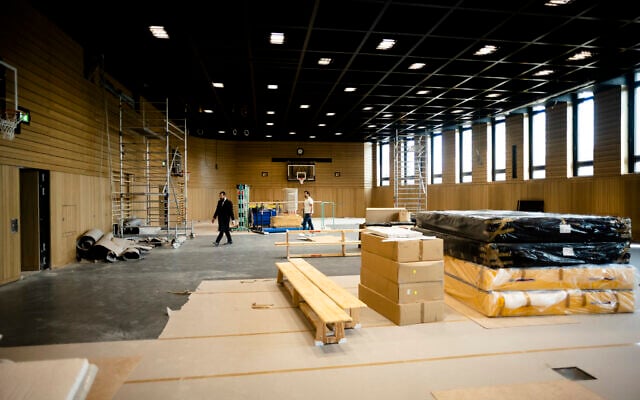 Rabbi Yehuda Teichtal, left, walks through the construction site of a huge indoor basketball court and gym that can be turned into a lecture hall for up to 600 people or a reception hall for weddings and bar mitzvahs, inside the new Jewish educational and cultural complex in Berlin, Germany, Monday, June 12, 2023. (AP Photo/Markus Schreiber)