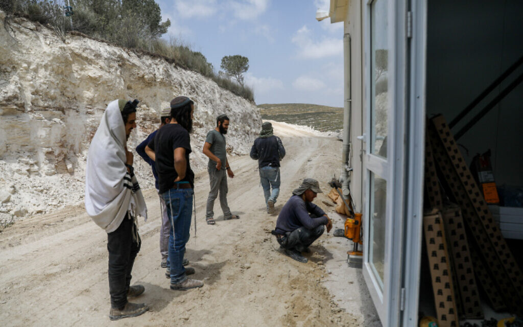 Settlement activists, one of whom is wearing a prayer shawl and tefillin, at a construction site of the illegal West Bank outpost of Homesh, May 29, 2023. (Flash90) Settlement activists, one of whom is wearing a prayer shawl and tefillin, at a construction site of the illegal West Bank outpost of Homesh, May 29, 2023. (Flash90)