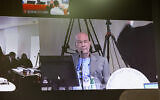 A video screen shows Arnon Milchan testifying remotely from England in Prime Minister Benjamin Netanyahu's corruption trial, on June 26, 2023.  ( Alex Kolomoisky/Pool/Flash90)