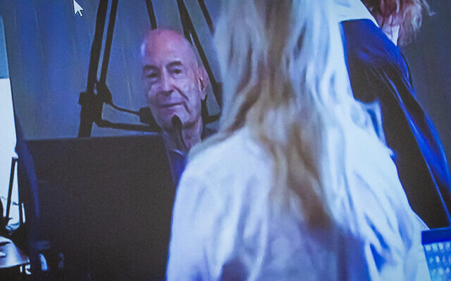 Sara Netanyahu, wife of Prime Minister Benjamin Netanyahu, and businessman Arnon Milchan seen on a screen before his testimony in Netanyahu's Case 1000 corruption trial, in Brighton, on June 27, 2023. (Oren Ben Hakoon/POOL)