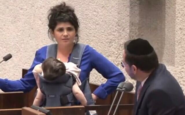 Screen capture from video of National Unity MK Sharren Haskel, left, wearing her baby daughter in a sling, and Deputy Knesset Speaker of Shas, Uriel Buso, in the Knesset, June 27, 2023. (Twitter. Used in accordance with Clause 27a of the Copyright Law) Screen capture from video of National Unity MK Sharren Haskel, left, wearing her baby daughter in a sling, and Deputy Knesset Speaker of Shas, Uriel Buso, in the Knesset, June 27, 2023. (Twitter. Used in accordance with Clause 27a of the Copyright Law)