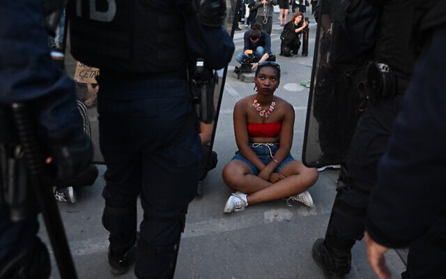 A protester sits in front of CRS riot police during a demonstration at Place de la Concorde in Paris on June 30, 2023, over the shooting of a teenage driver by French police in a Paris suburb on June 27 (Emmanuel DUNAND / AFP)