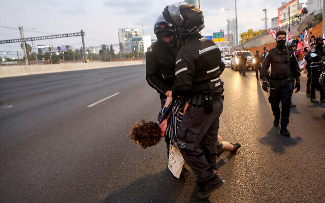 Police detain a man as demonstrators block the Ayalon Highway during a rally in Tel Aviv to protest the government's judicial overhaul plan, on July 1, 2023. (Photo by GIL COHEN-MAGEN / AFP)