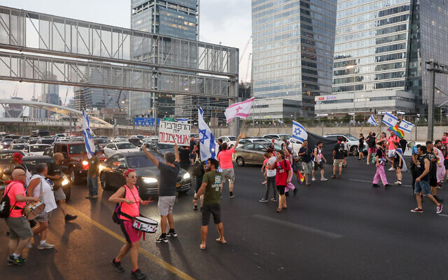 Demonstrators lift banners and flags as they block the Ayalon Highway during a rally in Tel Aviv to protest the government's judicial overhaul plan, on July 1, 2023. (Photo by GIL COHEN-MAGEN / AFP)