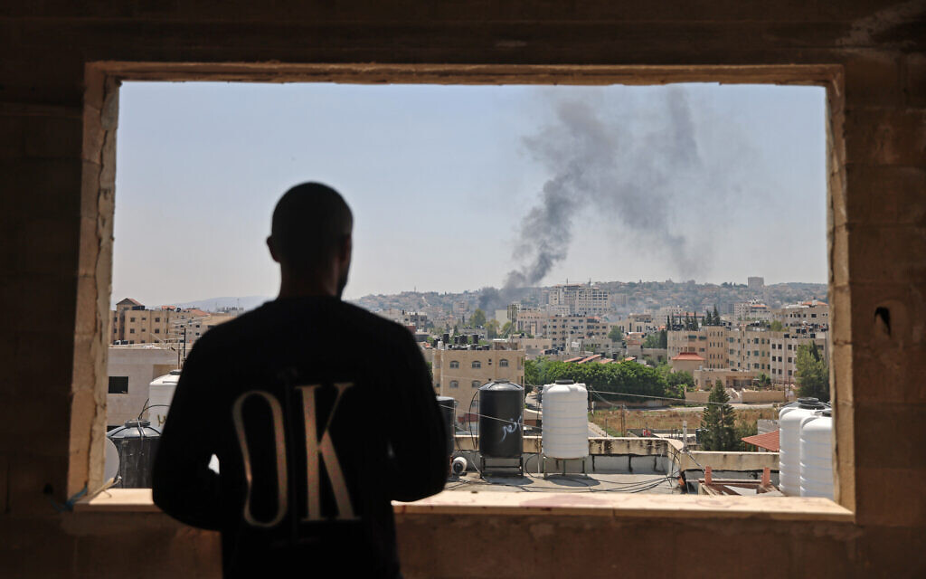A Palestinian man looks out the window as smoke billows following an Israeli drone strike in the West Bank city of Jenin, on July 3, 2023. (Jaafar Ashtiyeh/AFP) A Palestinian man looks out the window as smoke billows following an Israeli drone strike in the West Bank city of Jenin, on July 3, 2023. (Jaafar Ashtiyeh/AFP)