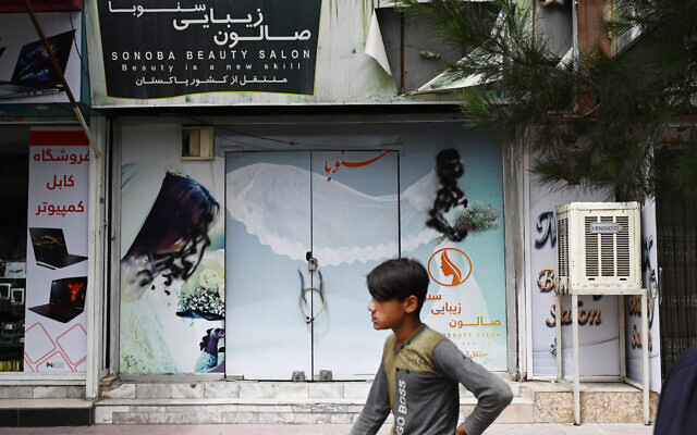 A youth walks past a closed beauty salon with images of women defaced at Shahr-e Naw area in Kabul on July 4, 2023. (Wakil Kohsar/AFP) A youth walks past a closed beauty salon with images of women defaced at Shahr-e Naw area in Kabul on July 4, 2023. (Wakil Kohsar/AFP)