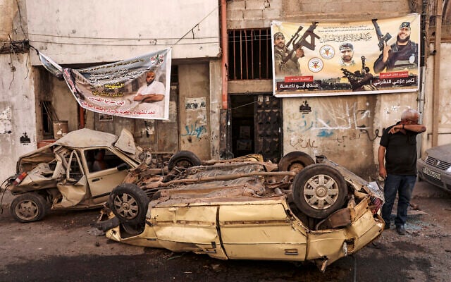 A man stands next to wrecked cars in the aftermath of an Israeli military operation in the Jenin refugee camp in the West Bank on July 5, 2023. (Ronaldo Schemidt/AFP)