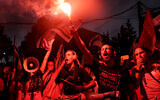 A demonstrator from the 'Pink Front' group lights a flare while others in a marching band perform with drums during a protest against the Israeli government's judicial overhaul plan in Tel Aviv on July 8, 2023. (JACK GUEZ / AFP)