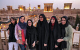 Women pose for a group photo with wind catchers ("badir" in Persian) dotting the skyline behind, on a rooftop in Iran's central city of Yazd on July 3, 2023. (Photo by ATTA KENARE / AFP)