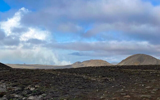 Smoke billowing from flowing lava is seen in the distance during an volcanic eruption near Litli Hrutur, southwest of Reykjavik in Iceland, on July 10, 2023. (Jeremie RICHARD / AFP)